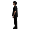 A sideview of a model, showcases an elegant black T-shirt with the white brand name FRIEDENMEER embroidered across the chest, paired with matching black trousers and shoes, highlighting the brand's sleek elegance and luxury.