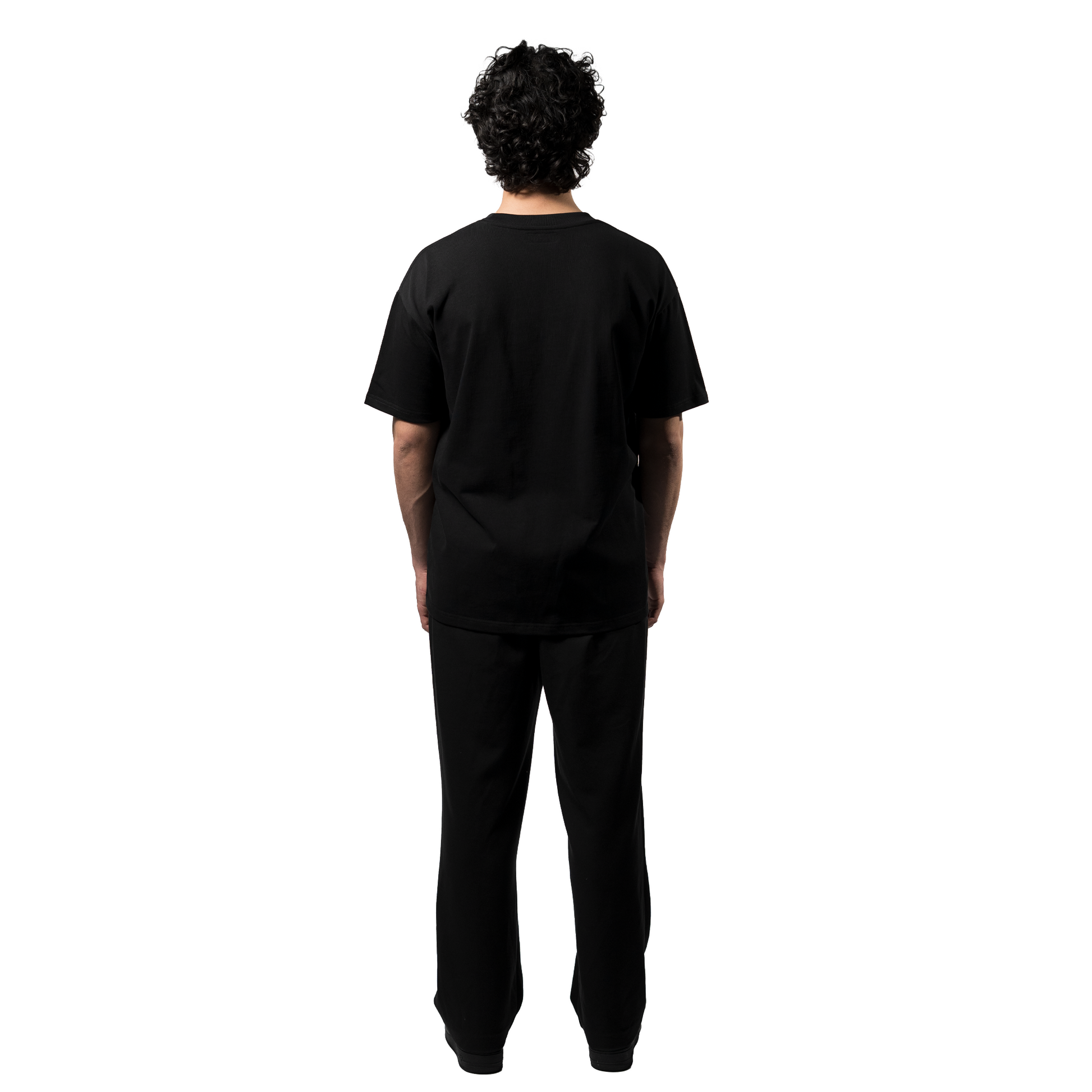 A back view of an model showcasing an elegant black oversized T-shirt, paired with matching black trousers and shoes, highlighting the brand's sleek elegance and luxury.